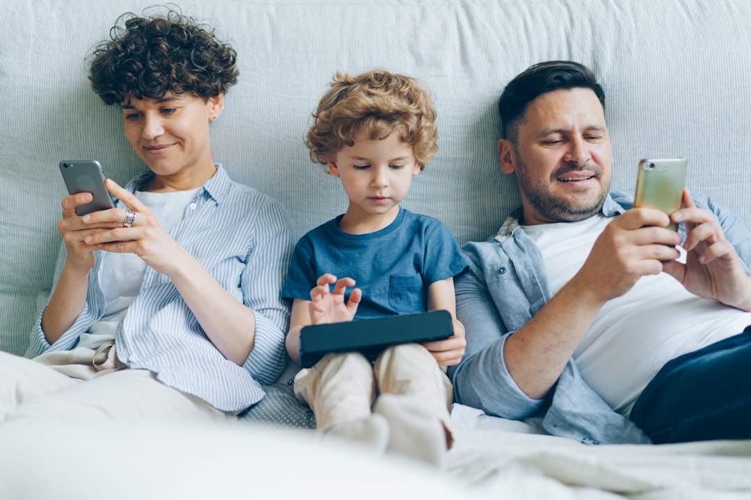 AI時代の新常識：ChatGPTが変える子育てと現代の親の役割 - Man and woman using smartphones while kid playing game on tablet in bed at home