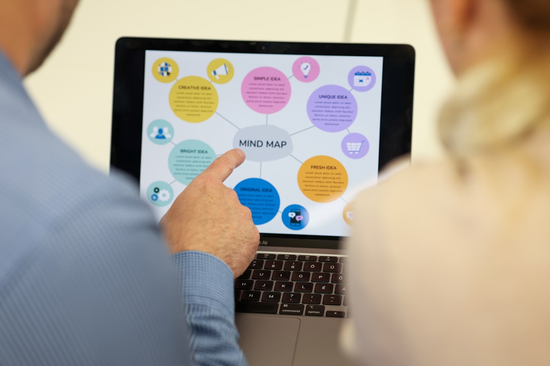 【ChatGPT】最新アップデート！ブレインストーミング特化機能がリリース - Two people viewing a mind map displayed on a laptop screen, one person pointing at the central idea labeled 