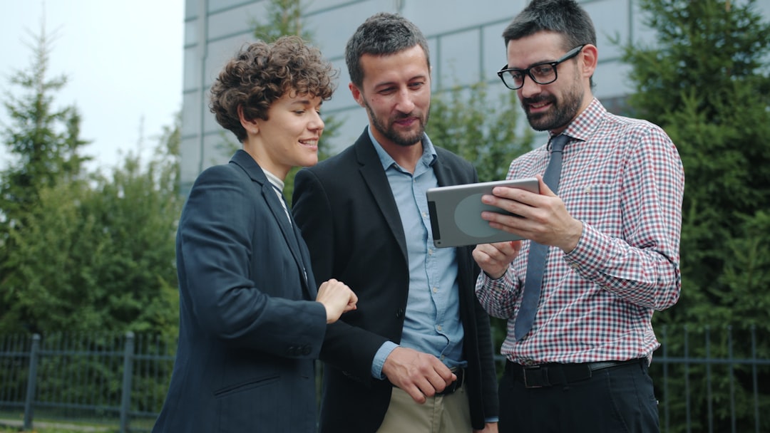 OpenAIが企業AI導入の「最後の一哩」へ挑む！新会社設立の真意を分析 - Slow motion of happy young colleagues guys and girl standing outdoors discussing work holding tablet portable computer. People and communication concept.